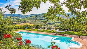 Une piscine avec vue sur un vignoble et des collines en arrière-plan.