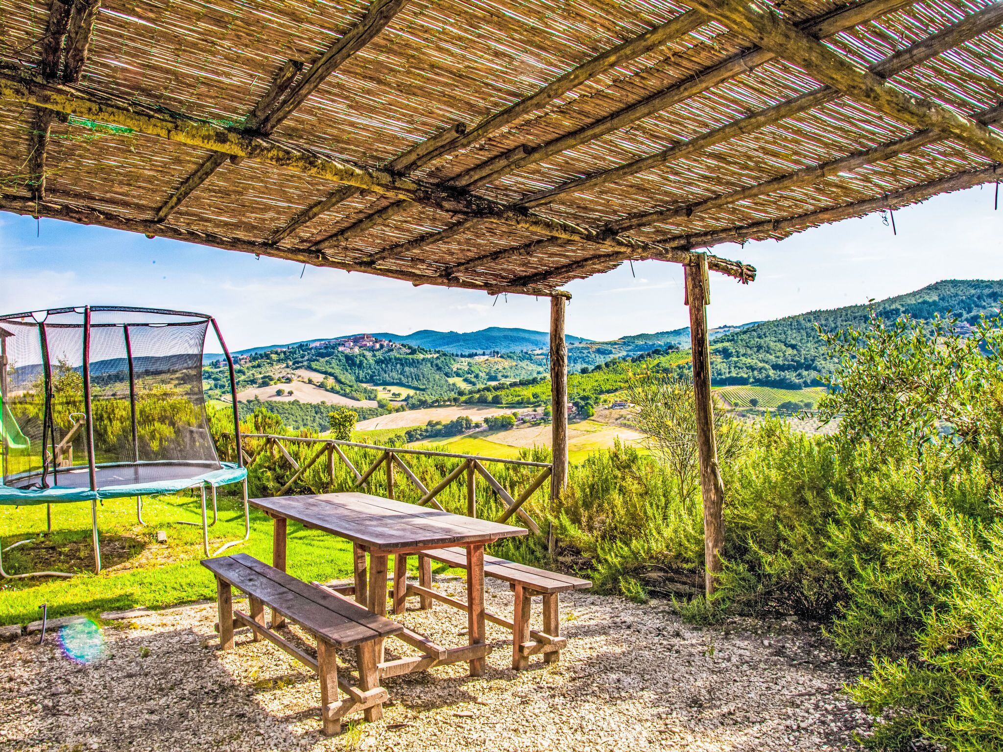 Un'area esterna riparata con un trampolino, tavolo da picnic e panchina.