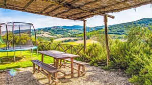 Un espace extérieur abrité comprenant un trampoline, une table de pique-nique et un banc.
