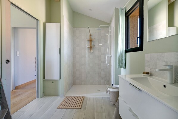 A modern bathroom with a shower, a sink, and a mirror.