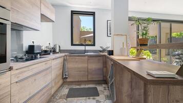 A modern kitchen with wooden cabinets, a built-in stove, and a large window.