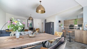 A modern kitchen with a wooden island, bar stools, and a dining area with a wooden table and chairs.