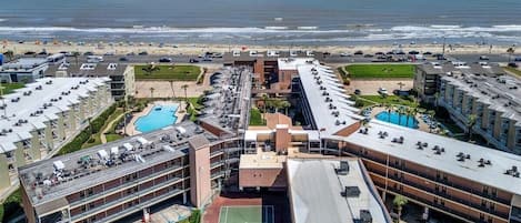 A hotel with multiple buildings, a tennis court, and a pool area.