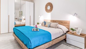 Ein Schlafzimmer mit Bett, Nachttischen, einem Kleiderschrank, einem Spiegel und einer Wandleuchte.