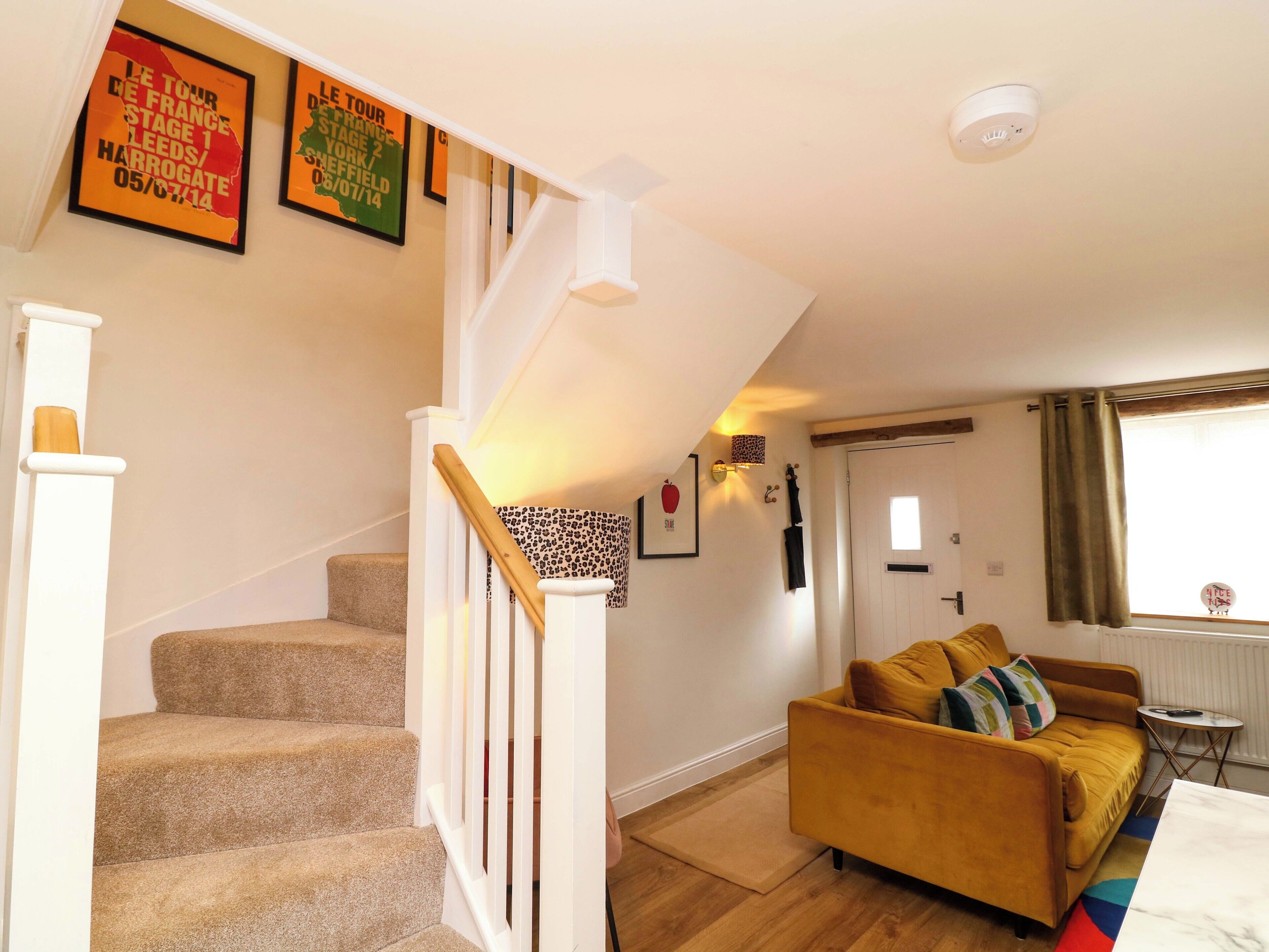 Eine Treppe mit weißer Handlauf, einem gelben Sofa und einem gerahmten Poster an der Wand.