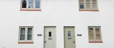 Un bâtiment à deux étages, doté d’une façade blanche, de portes numérotées et de fenêtres avec des volets.