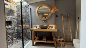Un bagno con parete in pietra, un mobile lavabo in legno, uno specchio grande, un lampadario e una scala.