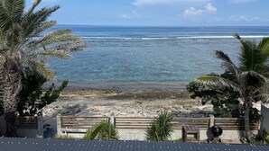 Una proprietà fronte spiaggia con vista sull'oceano, un pontile di legno e palme.