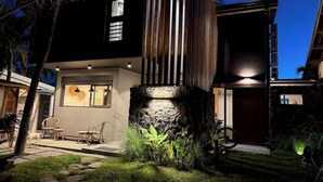 Una casa moderna con un elemento in pietra, posti a sedere all'aperto e un ingresso ben illuminato.