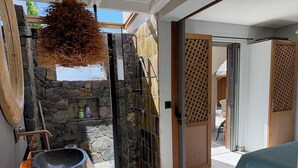 Un bagno moderno con parete in pietra, un ampio lavabo e una panca in legno.