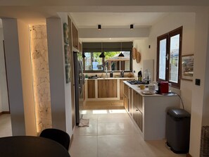 Une cuisine moderne dotée d’un îlot central, de meubles en bois et offrant une vue sur l’extérieur.