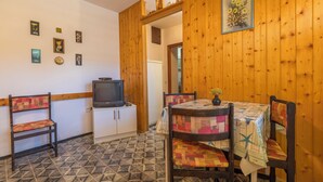 Una habitación con paredes de madera, un televisor, una mesa con colcha y suelo estampado.