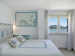A bedroom with a bed, a map on the wall, a window with a view of the sea, and a small table. - Anita Bados by Interhome (Pittulongu)