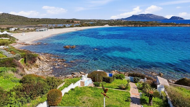 A coastal view with clear blue waters, a sandy beach, and a mountainous backdrop. - Anita Bados by Interhome (Pittulongu)