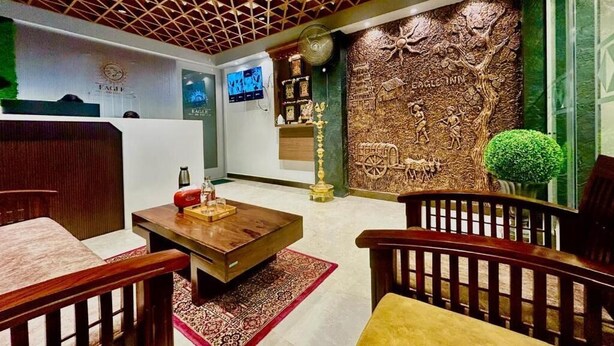 A reception area with a wooden ceiling, a reception desk, a wall with a tree relief, and a small green plant.