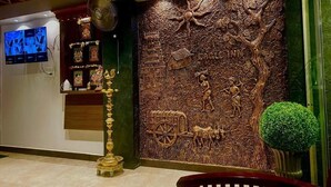 A reception area with a wall mural, a television, and a traditional lamp.