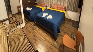 A room with two beds, a ceiling fan, a TV, and a window with curtains.