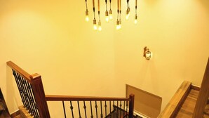 A staircase with a wooden handrail and black balusters, leading to a landing with a light fixture.