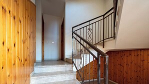 Una scala con rivestimenti in legno a sinistra e ringhiera in metallo a destra.