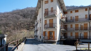 Un edificio a più piani con balconi, un cartello di divieto di accesso e una vista su un paesaggio collinare.