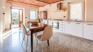 Une cuisine avec un plafond en briques, des armoires blanches, une table à manger avec des chaises et une fenêtre.