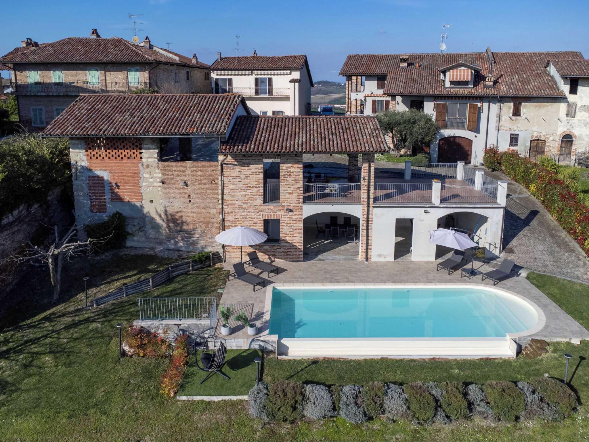 A residential property with a swimming pool, outdoor seating, and a view of neighboring houses.