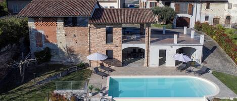 A residential property with a swimming pool, outdoor seating, and a view of neighboring houses.