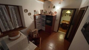 Una cocina compacta con refrigerador, un comedor con mesa y sillas, y una pequeña mesa de comedor al fondo.