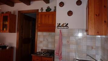 A kitchen with wooden cabinets, a gas stove, a tiled backsplash, and a hanging towel.
