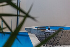 A poolside area with a table and chairs, a glass of water, and a book. - Holiday Home Vele With Pool (Vrgorac)