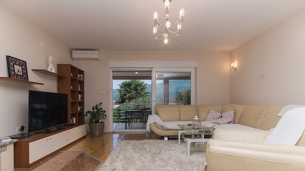 A living room with a TV, sofa, coffee table, and a view through a sliding door. - Holiday Home Vele With Pool (Vrgorac)