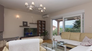 A living room with a sofa, a glass coffee table, a TV, and a bookshelf. - Holiday Home Vele With Pool (Vrgorac)