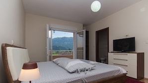 A bedroom with a bed, a TV, a lamp, and a view of mountains. - Holiday Home Vele With Pool (Vrgorac)