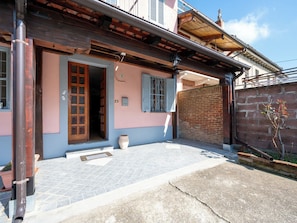 A building with a tiled patio, a wooden door, and a brick wall.