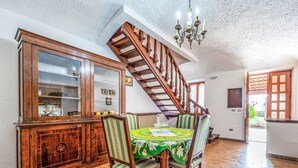 Ein Essbereich mit einer Holztreppe, einer Chandelier und einem Esstisch mit Stühlen.