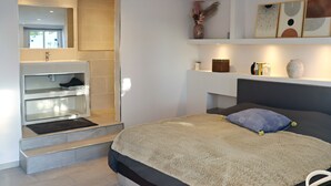 Une chambre à coucher moderne avec un lit, des étagères intégrées, un miroir et un espace douche.