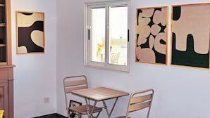 Une pièce avec une table et des chaises, une fenêtre et des œuvres d’art abstraites accrochées au mur.