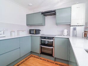 Una cocina moderna con horno integrado, microondas y cafetera.