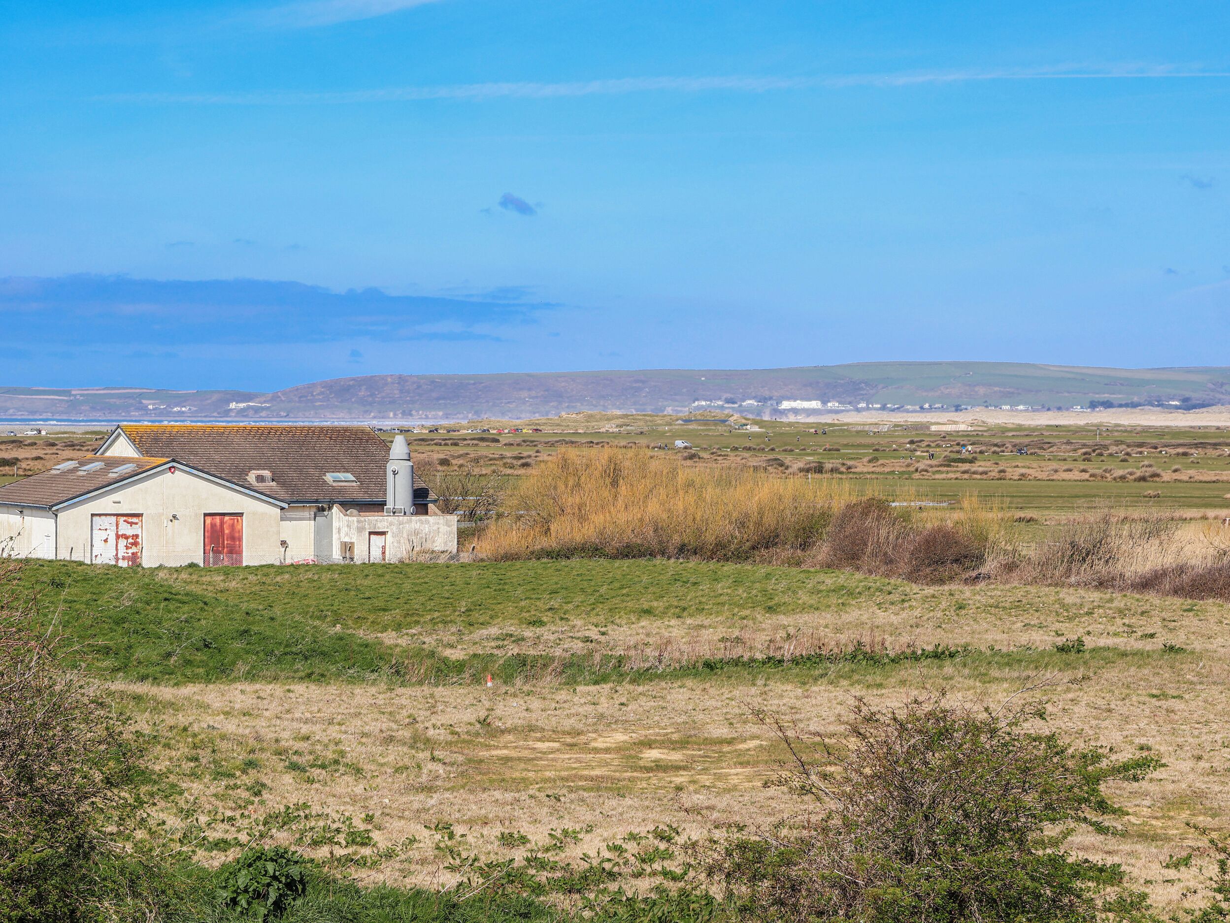 A rural landscape with a small white building featuring a red door and a chimney.