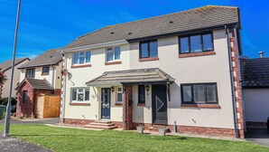 A two-story residential building with a front porch, a garage, and a well-maintained lawn. - Sea Spray (Bideford)