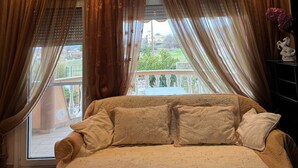 A bedroom with a bed, curtains, and a view of a balcony.
