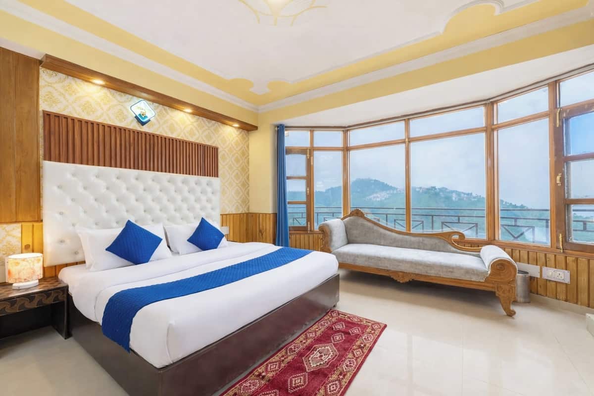 A bedroom with a large bed, a sofa, a view of the outdoors, and a decorative ceiling.