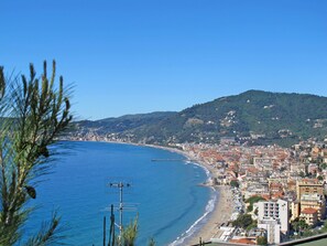 Eine Küstenstadt mit Strand, Gebäuden und einer Hügelkette im Hintergrund.
