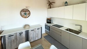 A modern kitchen with white cabinets, a built-in oven, a microwave, and a large island with a sink. - Belle Vue by Interhome (Alassio)