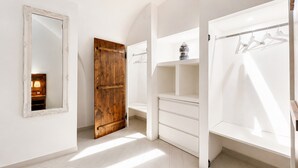 A room with a large mirror, wooden door, white wardrobe, and a hanging rack. - Casa Marosa – In the Heart of the Village (Monte Sant'Angelo)