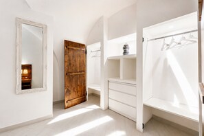 Une pièce dotée d’un grand miroir, d’une porte en bois, d’une armoire blanche et d’un porte-vêtements suspendu.