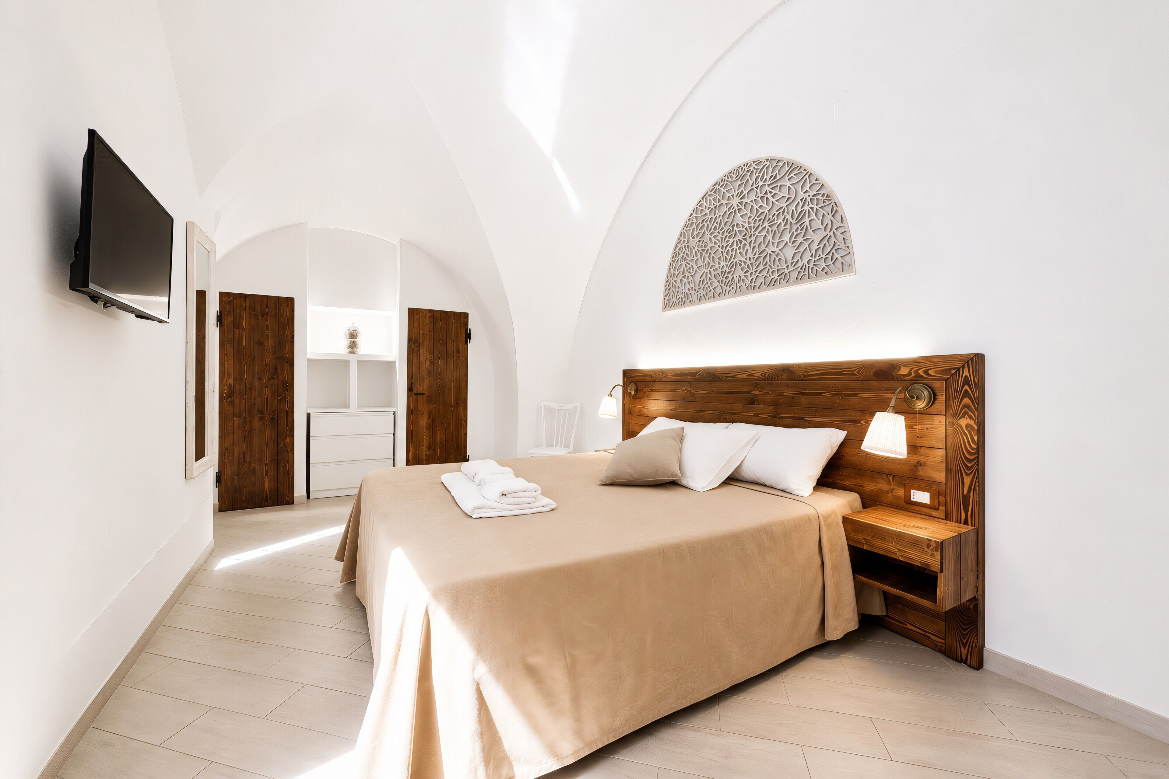 Ein Schlafzimmer mit einem Bett, einem Nachttisch, einem Fernseher und einem Holz-Kopfteil.