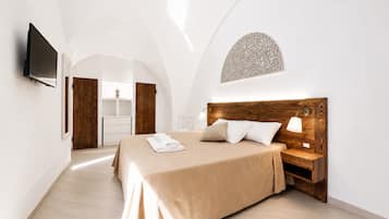 Ein Schlafzimmer mit einem Bett, einem Nachttisch, einem Fernseher und einem Holz-Kopfteil.