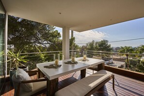 Ein Balkon mit Tisch, zwei Stühlen, einer Bank und einem Blumentopf.