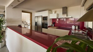 Een moderne keuken met een rode aanrecht, roestvrijstalen apparatuur en een rode achterwand.